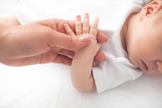 Close-up of female hand holding the babu armA young and beautiful mother is holding a newborn baby in her arms, taking care of him at home.