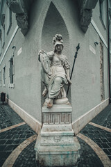 Budapest, Hungary - 2021: Statue of Pallas Athene in the corner of a building near Matthias Church at Trinity Square. God of wisdom depicted with a sword and a shield bearing the coat of arms of Buda.