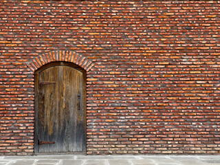 Red brick wall with arched wooden door