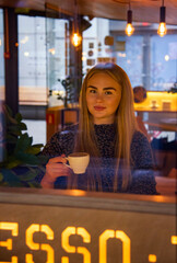 beautiful blonde woman with long hair drinking coffee in cafe