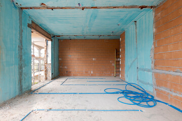 Interior of an ancient villa under renovation with blue painted walls, electrical pipes on the ground and freshly laid orange bricks