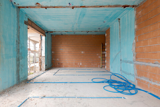 Interior of an ancient villa under renovation with blue painted walls, electrical pipes on the ground and freshly laid orange bricks