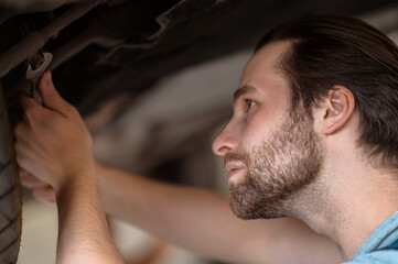 Fototapeta premium Focused young Caucasian automotive technician repairing the customer vehicle
