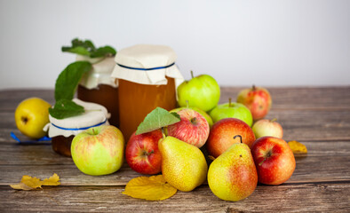 Ripe apples and pears and jars of apple jam on the table