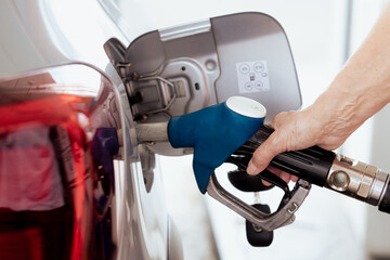 Woman hand filling fuel into the car tank at the pump service station, for concept transportation...