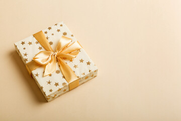wrapped Christmas or other holiday handmade present in white paper with gold ribbon on colored...