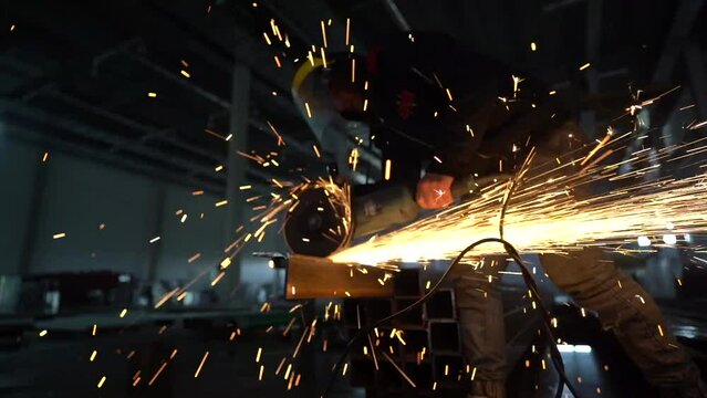 Slow motion. Professional male worker works cutting metal with a grinding machine