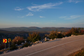 Empty car road in middle of nowhere. Croatia, mountains and desert, sunrise in autumn colors. No people