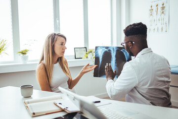 Fototapeta premium The doctor is analyzing and clarifying images of the patient's lung X-rays. Doctor showing female patient x-ray shot in clinic office. Coronavirus chest X-ray. 