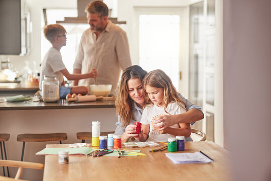 Mother painting with child and father cooking with kid in their family home together for growth development and learning. Parents or people teaching children, having fun in kitchen or a holiday house