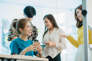 Asian creative teams sit and work together to share inspirational creativity in a workshop. Young modern businessmen are meeting with graph paper and laptop in the workplace.