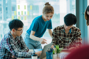 Asian creative teams sit and work together to share inspirational creativity in a workshop. Young modern businessmen are meeting with graph paper and laptop in the workplace.