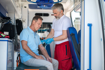 Ambulance doctor preparing the patient for an intravenous infusion procedure