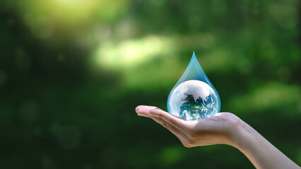 Water drop in hand against natural background in Save water concept on world water day. Conserving...