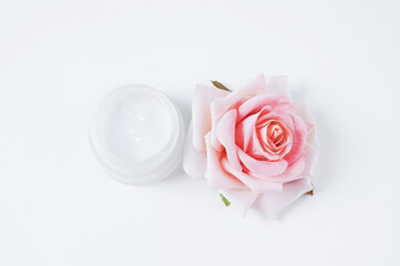  jar of face cream and a rose bud on  white background.