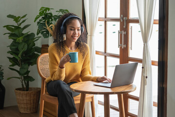 An African American woman uses a laptop, smartphone, tablet and music headset in her home to relax.