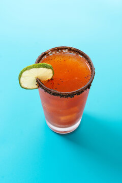 Homemade michelada cocktail with beer, lime juice,hot sauce,salted Rim and tomato juice on blue background