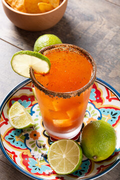 Homemade michelada cocktail with beer, lime juice,hot sauce,salted rim and tomato juice on wooden table