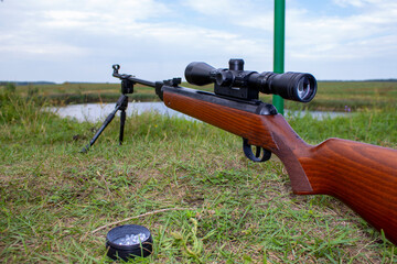 Pneumatic rifle for shooting with an optical sight on the background of grass on the hunt