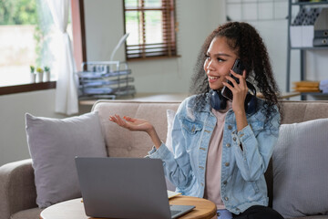 African woman, American, using laptop computer and wearing headphones for online learning.