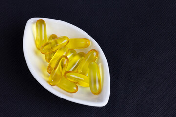 Fish oil in white bowl on black background.