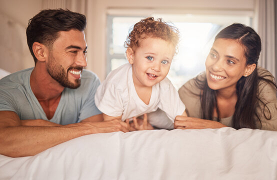 Happy, Love And Parents With Their Baby On Bed In The Bedroom Bonding, Playing And Relaxing At Home. Happiness, Smile And Couple Laying With Their Child In Hotel Room While On Family Holiday Together