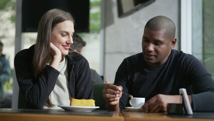 Happy couple seated at coffee shop. Diverse man and woman at cafe place. Two people at restaurant