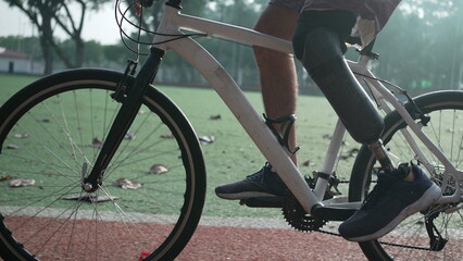 Fototapeta premium Person with prosthetic leg riding bicycle outdoors. A disabled athlete rides bike