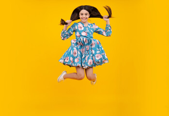 Full size length of young brunette girl teen student jump run go move hurry up isolated on yellow background studio.