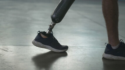 Disabled person walking with his prosthetic leg indoors. Amputee man walks with prosthetic leg