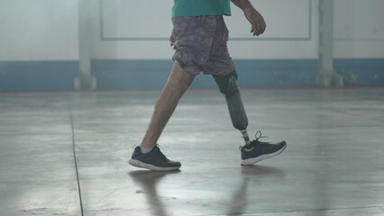 Disabled person walking with his prosthetic leg indoors. Amputee man walks with prosthetic leg