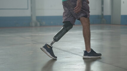 Disabled person walking with his prosthetic leg indoors. Amputee man walks with prosthetic leg