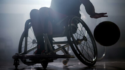 Disabled basketball player in wheelchair with dramatic lighting. Athlete with disability hard backlight