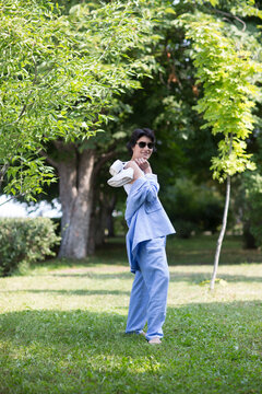 middle aged woman  in a suit without sneakers walks barefoot on the grass in the park. Enjoying the little things. Lykke concept. Relaxation Concepts
