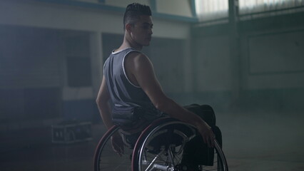 Disabled athletic man in wheelchair with dramatic hard backlight. Mobility and motivation concept
