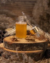 Opened cosmetic dropper bottle filled with yellow serum on wood near natural boho decor