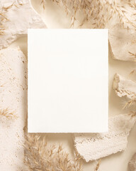 Blank card near beige travertine stones and dried pampas grass top view, greeting mockup