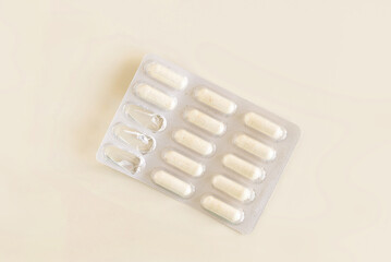 Capsules in a used plastic blister package on light beige top view. Taking dietary supplements