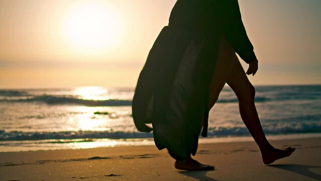Bare woman legs stepping on wet seashore at sunrise closeup. Girl walking beach.