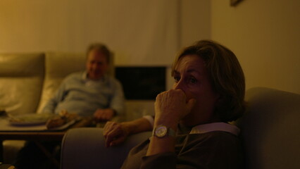 Obraz premium Baby boomer generation watching television at living room. Older senior people sitting on couch sofa