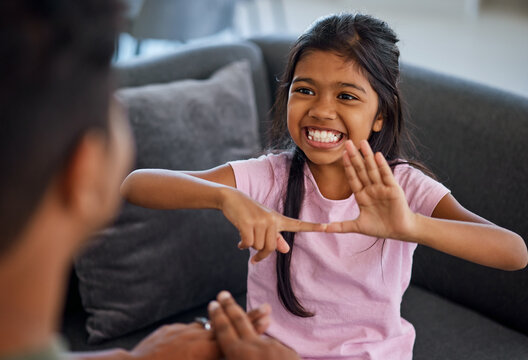 Child, sign language and learning to communicate with deaf girl or parent while making fingers and showing visual symbols at home. Happy kid with hearing disability or loss sitting with a tutor