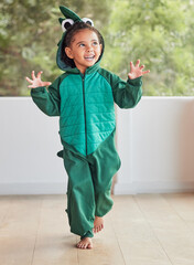 Child, smile and excited in halloween dinosaur costume at home playing role and having fun at...
