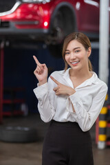 portrait asian woman smile finger pointing empty space standing at service engine mechanic garage, woman car insurance officer. Repair service and car insurance concept.