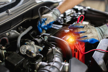 Transportation repair service concept, Repairman auto mechanic Checking battery power of car after...
