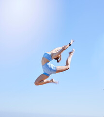 Fitness, jumping and sky with a sports woman mid air outdoor against a clear blue background during summer. Workout, exercise and training with a female athlete leaping for health and wellness
