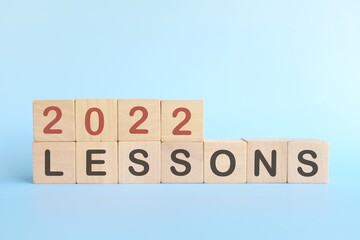 Year 2022 life lessons and learnings concept. Wooden blocks in blue background.