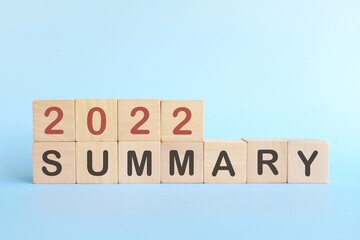 Year end 2022 review and summary concept. Wooden blocks in blue background.	