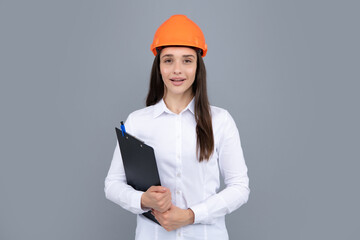 Young woman in hard hat helmet with clipboard isolated on grey background. Architect woman wear helmet and shirt. Business woman, construction manager, builder.
