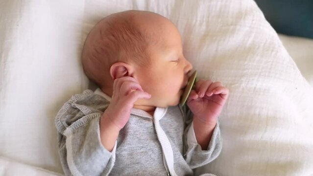 newborn with pacifier. baby close-up with a pacifier lies in bed at home indoors. happy family maternity hospital kid lifestyle dream concept. newborn baby boy with pacifier close-up