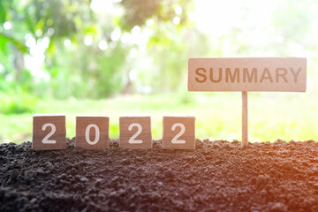 Year end 2022 review and summary concept. Wooden blocks in dark sunset on natural background.	